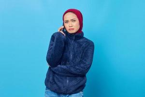 jovem asiática triste falando ao celular com o namorado, isolada em um fundo azul