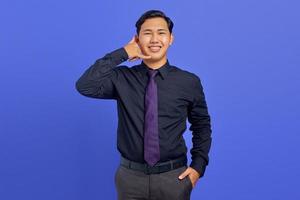 bonito homem asiático mostrando gesto de ligação no fundo roxo foto