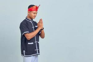 retrato de jovem asiático vestindo quimono taekwondo com gesto de saudação em fundo cinza foto