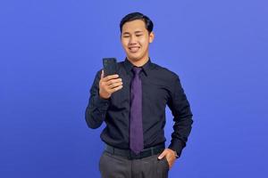 retrato de um jovem empresário sorridente usando smartphone em fundo roxo foto
