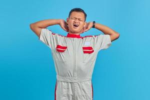 retrato de um jovem mecânico asiático com sono e boca aberta sobre um fundo azul