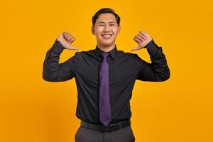 retrato de um jovem empresário asiático sorridente, apontando para si mesma com orgulho em fundo amarelo foto