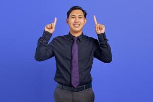 retrato de jovem asiático alegre apontando para a promoção de anúncios diretos em fundo roxo foto
