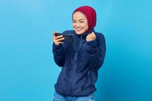 retrato de uma mulher asiática entusiasmada jogando no celular e comemorando a vitória foto