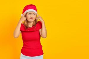 retrato de uma jovem pensativa com chapéu de Natal, tendo dúvidas e pensando sobre fundo amarelo foto