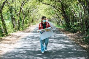 turistas femininas ficam de pé e olham para o mapa na estrada. foto