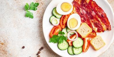 pequeno-almoço inglês bacon, ovo, tomate, pepino, pão torrado foto
