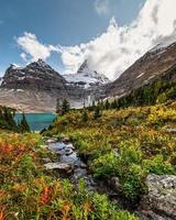 monte assiniboine com riacho fluindo na floresta de outono no lago magog no parque nacional foto