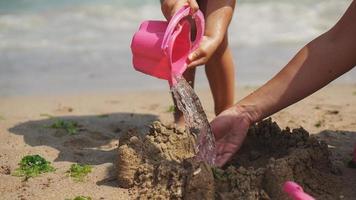 criança construindo com castelo de areia. momento nostálgico tão feliz. crianças brincando com brinquedos interativos de plástico na praia. foto