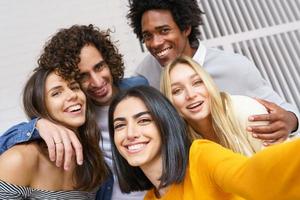 grupo multiétnico de amigos tirando uma selfie juntos enquanto se divertem ao ar livre. foto