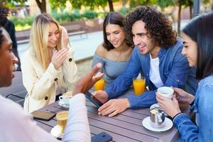 grupo multiétnico de amigos tomando uma bebida juntos em um bar ao ar livre. foto