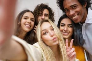 grupo multiétnico de amigos tirando uma selfie juntos enquanto se divertem ao ar livre.