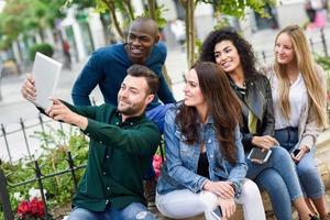 jovens multiétnicos fazendo selfie juntos em meio urbano foto