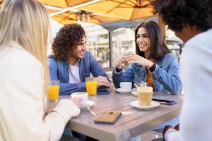 grupo multiétnico de amigos tomando uma bebida juntos em um bar ao ar livre. foto