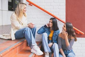 grupo multiétnico de três amigos sentados na rua conversando. foto