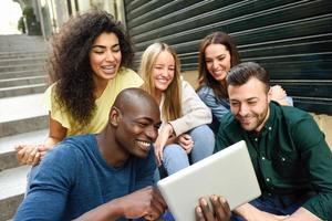 grupo multiétnico de jovens olhando para um computador tablet foto