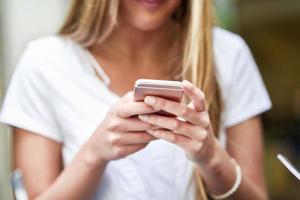 imagem de close-up de uma jovem loira enviando mensagens de texto com smartphone foto