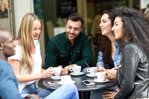 grupo multirracial de cinco amigos tomando um café juntos foto