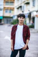 um jovem com uma camisa listrada está parado na rua. foto