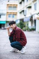 um jovem com uma camisa listrada sentado na rua foto