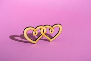 coração duplo de madeira em um fundo rosa. celebrando o espaço da cópia do dia dos namorados. foto