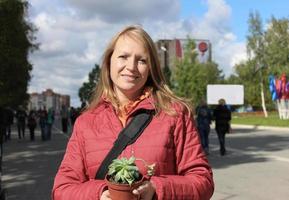 Mulher de meia-idade feliz segurando uma planta suculenta em um vaso foto