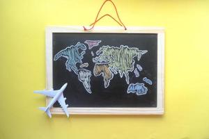 conceito de viagens com um avião no mapa mundial afogado no quadro de giz foto