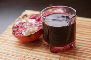 copo com suco de romã sobre fundo vermelho. foto