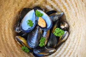 mexilhões com ervas limão no fundo de comida do vaporizador de cozinheiro - frutos do mar frescos marisco no restaurante comida de casca de mexilhão na cesta do vaporizador de bambu foto