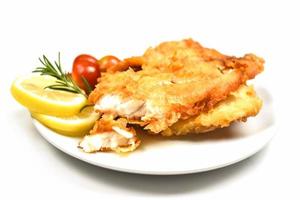 Filé de peixe frito fatiado para bife ou salada cozinhando comida com ervas especiarias alecrim e limão - filé de tilápia crocante de peixe servido em prato branco foto