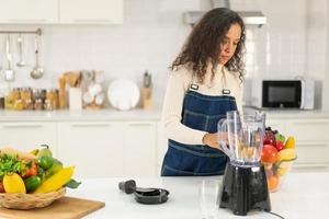 mulher latina fazendo suco na cozinha foto