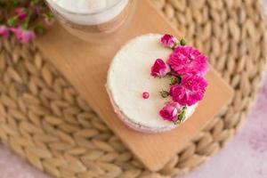 um pequeno bolo de branco e rosa decorado com flores e frutos silvestres foto