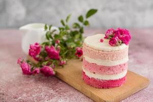 um pequeno bolo de branco e rosa decorado com flores e frutos silvestres foto