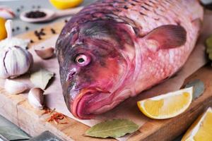 peixes comerciais de rio carpa selvagem na tábua com ingredientes para cozinhar foto