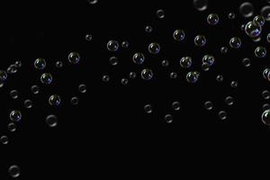 padrão de sabão de bolhas transparentes sobreposição de respingos de partículas abstratas de água no preto. foto