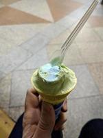 padrão de sobremesa congelada de sabor verde de sorvete na mão de copo preto segurando na madeira. foto