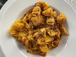 tortellini com molho à bolonhesa, tortellini al ragu à bolonhesa, com queijo parmigiano reggiano. foto