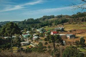 charmosas casas de campo subindo a colina em um vale com estradas e uma paisagem arborizada perto de bento gonçalves. uma simpática cidade do sul do brasil famosa por sua produção de vinho. foto