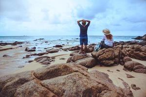 amantes asiáticos felizes na praia. o céu é a natureza de viagens brilhantes e sentar-se relaxar nas rochas no mar em phuket. Na Tailândia. verão. foto