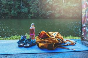 natureza de viagens. viajar relaxar. mochila e calçado telemóvel com um conjunto traveller.sun colocado na frente da tenda de campismo. fundo da natureza do Lago de montanha. foto