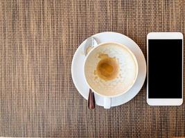 smartphone e xícara de café vazia na mesa de madeira em vista superior. foto