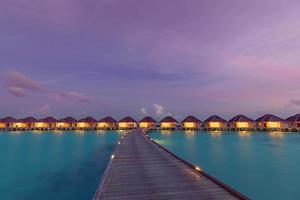 pôr do sol na ilha das Maldivas, resort de villas luxuosas na água e cais de madeira. lindo céu, nuvens e fundo de praia para férias de verão, férias e conceito de viagens