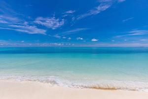 close up de areia na praia e céu azul de verão. paisagem panorâmica da praia. praia tropical vazia e vista do mar. céu alaranjado e dourado do pôr do sol, areia fofa, calma, luz solar tranquila e relaxante, clima de verão foto