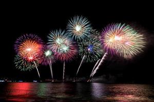 incríveis e lindos fogos de artifício coloridos na noite de celebração, mostrando na praia do mar com reflexo de várias cores na água