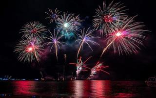 incríveis e lindos fogos de artifício coloridos na noite de celebração, mostrando na praia do mar com reflexo de várias cores na água