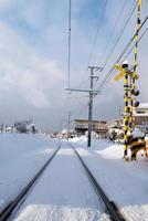 ferrovia para o trem local com queda de neve branca no inverno, japão foto
