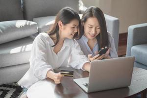 duas jovens usam laptop para fazer compras on-line pela internet durante a segurança em casa foto