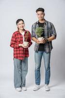 homens e mulheres de pé segurando vasos de plantas em casa foto