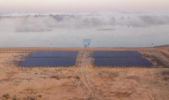 vista aérea do painel solar pela manhã à beira do lago para gerar energia e bombear água para a agricultura foto