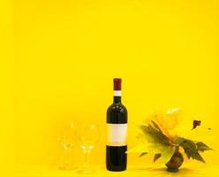 vinho com taças em fundo amarelo foto